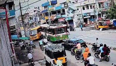Traffic scene in Jagtial with buses, cars, and motorcycles at an intersection.