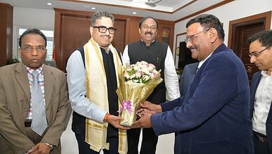 Group of men in formal attire exchanging a bouquet in an office setting.