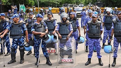CRPF officers in blue camouflage uniforms with helmets and shields during a security operation.