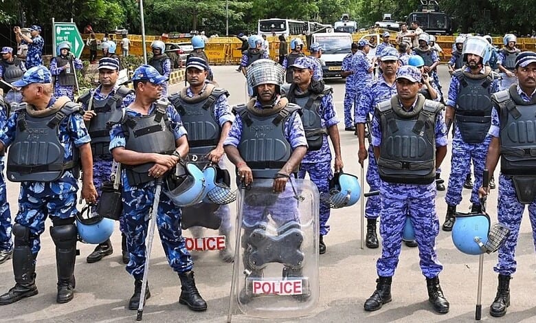 CRPF officers in blue camouflage uniforms with helmets and shields during a security operation.