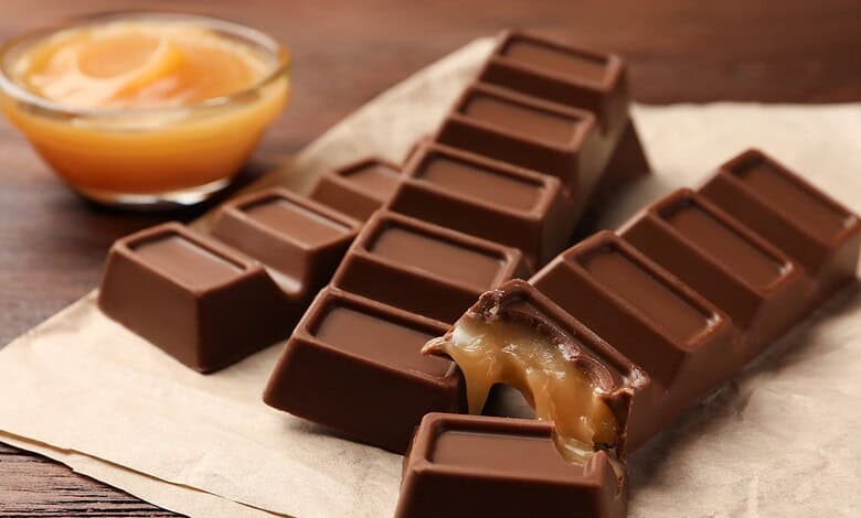 Close-up of a caramel-filled chocolate bar with a piece broken off, revealing the caramel inside.