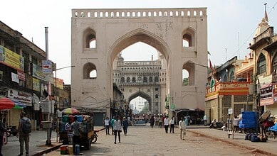 Historic Char Kaman arch in Hyderabad with busy street scene and shops.