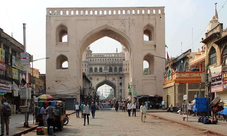 Historic Char Kaman arch in Hyderabad with busy street scene and shops.