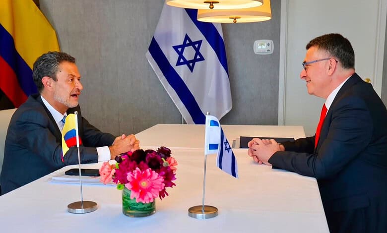 Diplomatic meeting between officials with flags of Colombia and Israel in the background.