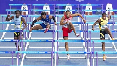 Athletes competing in hurdles race at a track and field event.