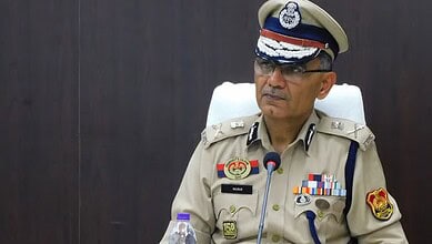 Tripura DGP Anurag in uniform at police headquarters, serious expression, wearing glasses.