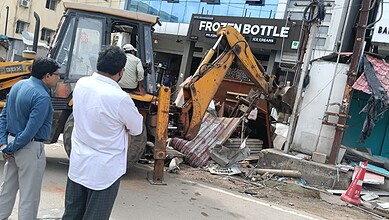 Construction machinery demolishing encroached structures on Hyderabad's DLF food street.