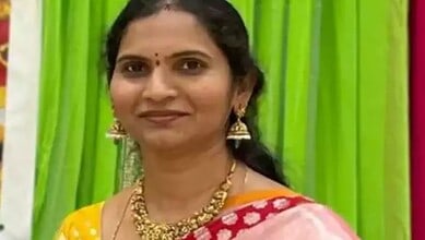 Indian woman wearing a yellow saree with red border and gold jewelry.