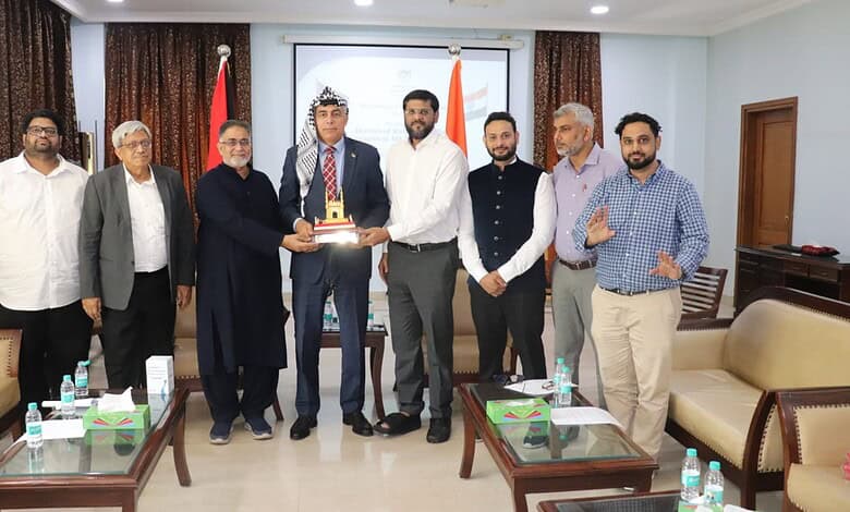 Group of men in formal attire at a meeting, with one man receiving a cake, in Hyderabad.