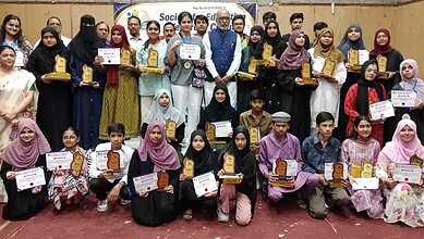 Group of students and teachers holding awards and certificates at a school event.