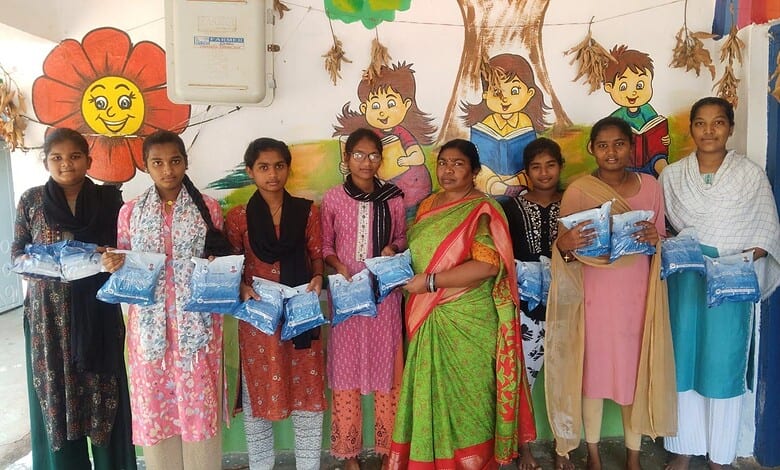Children at Anganwadi centre holding blue school supplies, with colourful wall art in the background.