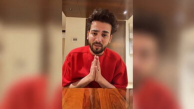 Elvish Yadav in a red shirt with folded hands, speaking to the camera.