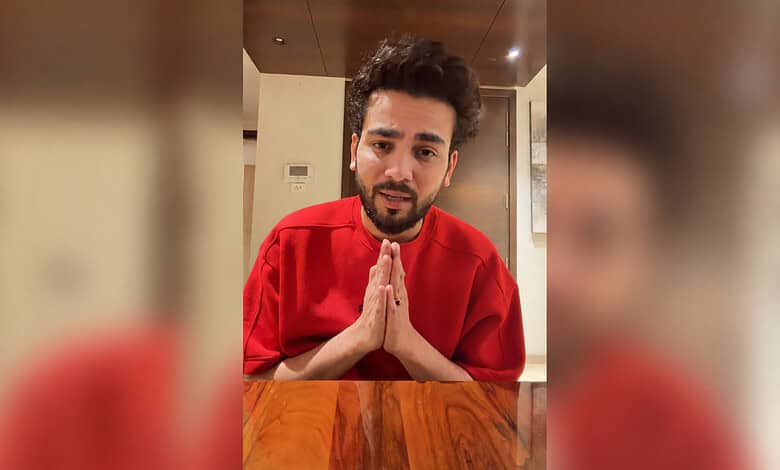 Elvish Yadav in a red shirt with folded hands, speaking to the camera.
