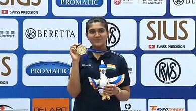 Esha Singh holding her gold medal and a dove mascot at the ISSF World Cup award ceremony.