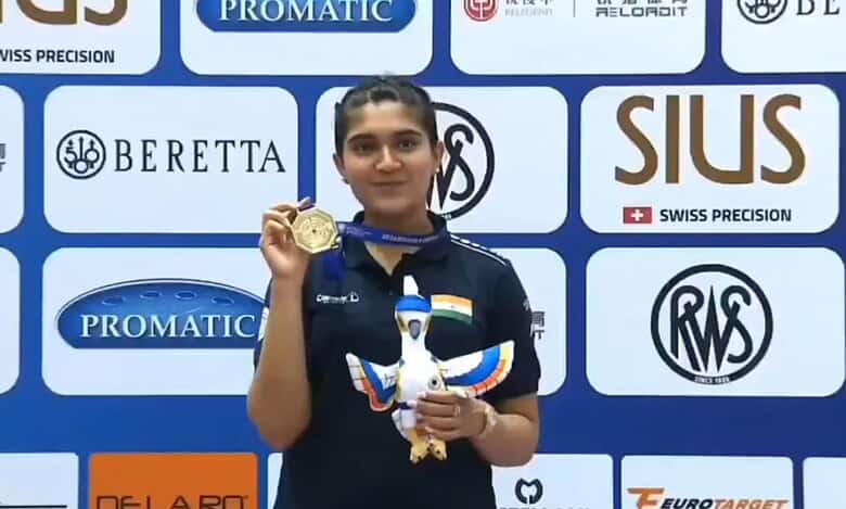 Esha Singh holding her gold medal and a dove mascot at the ISSF World Cup award ceremony.