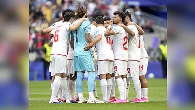 Iranian football team huddles during a match at FIFA World Cup, showing team unity.