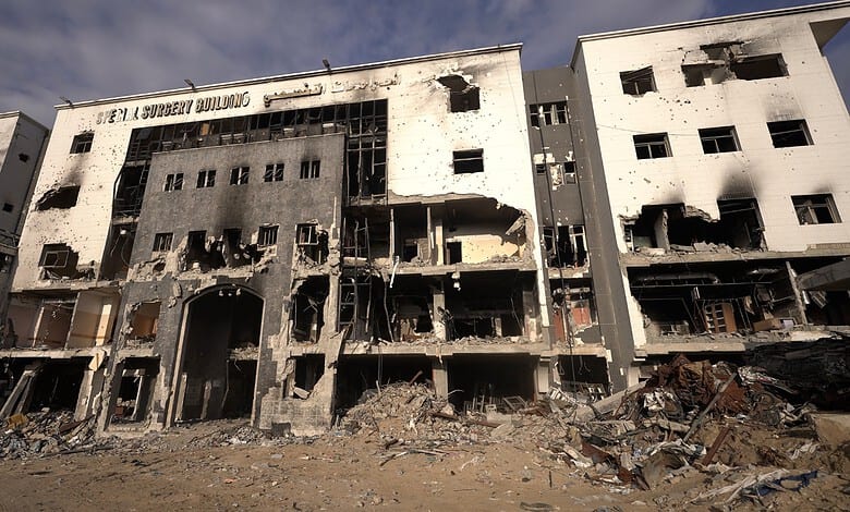 Damaged building with extensive fire and smoke damage, windows shattered, and debris on the ground.