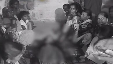 Group of villagers gathered around a person in distress in a rural setting.