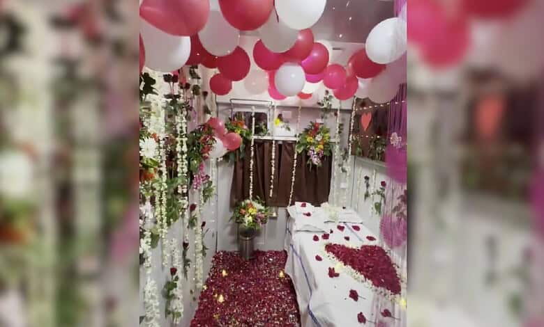 Honeymoon suite decorated with pink and white balloons, flowers, and rose petals on the bed.