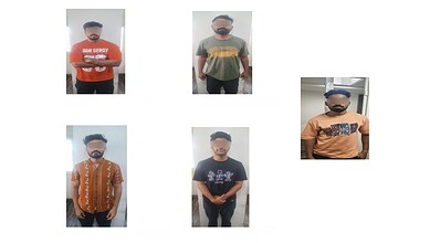 Group of five men with blurred faces, wearing casual T-shirts and standing indoors.