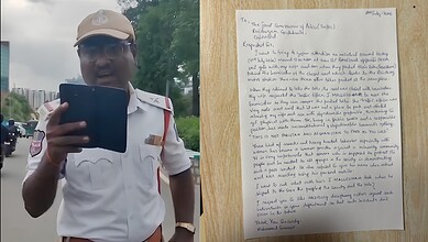 Police officer holding a tablet outdoors during daytime, wearing a white uniform and cap.