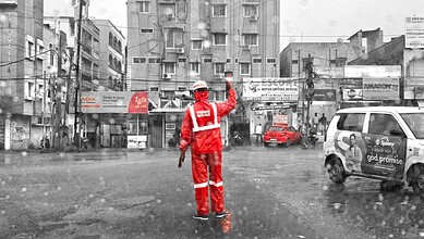 Traffic police officer in red uniform managing traffic during heavy rain in an urban area.