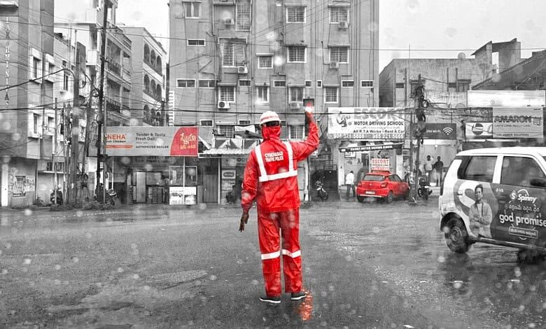 Traffic police officer in red uniform managing traffic during heavy rain in an urban area.