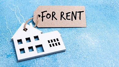 For rent sign with a house cutout on a blue background, symbolising rental property.