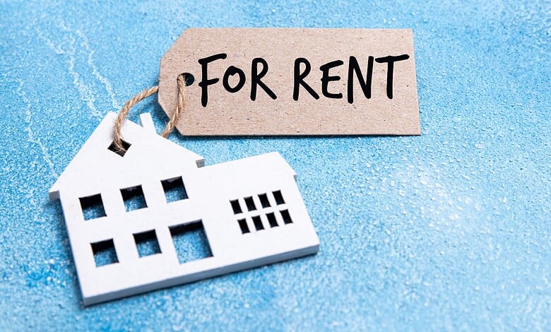 For rent sign with a house cutout on a blue background, symbolising rental property.