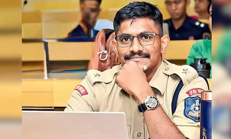 Trainee IPS officer in judicial custody, wearing uniform and glasses, sitting in court.