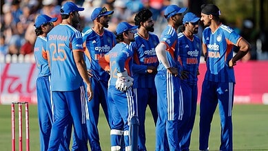 Indian cricket team players in blue uniforms during a match on the field.