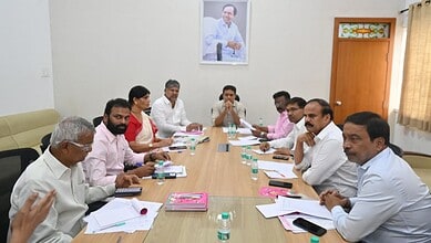 Group of men and women in a meeting room with documents and water bottles on the table.