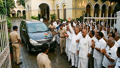 Karnataka Congress leaders and supporters gather around a vehicle during a political event.