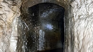 Ancient tunnel or cave entrance with stone walls and dark interior, possibly part of Mughal-era site.