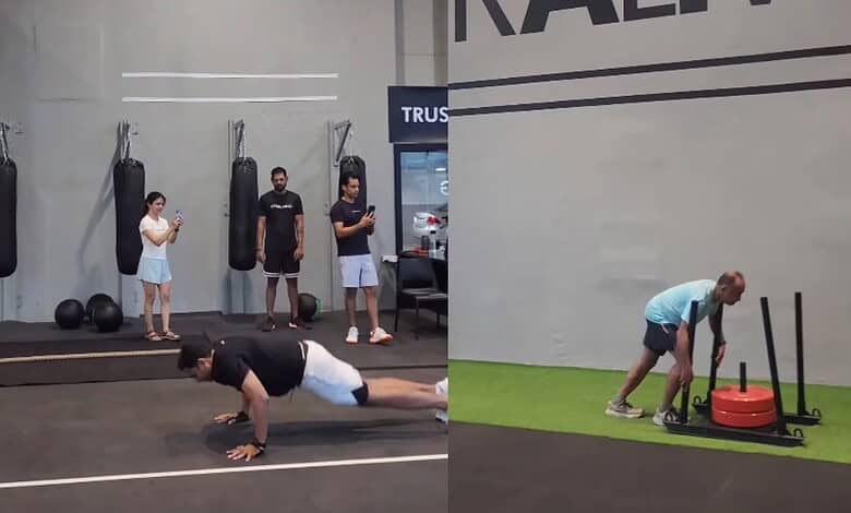 People working out in a gym with punching bags and a woman doing push-ups.