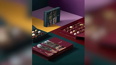 Assorted chocolates and packaging on colourful background, celebrating craft chocolate awards.