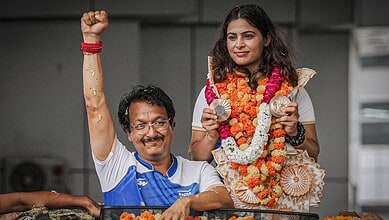 Manu Bhaker celebrates her bronze medal at the World Cup with a smile and victory gesture.