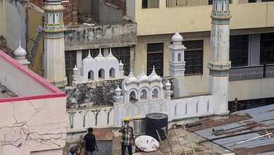 Construction site of a mosque with minarets and domes, showing ongoing building work.