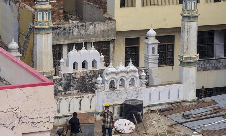 Construction site of a mosque with minarets and domes, showing ongoing building work.