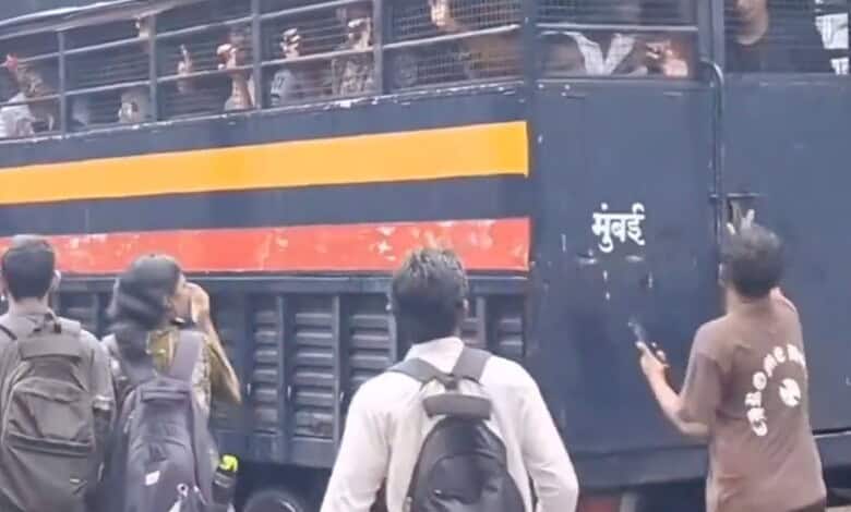 Man helps detained students escape from police van in a crowded street scene.