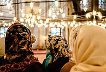 Muslim women wearing hijabs inside a mosque, engaged in prayer or reflection.