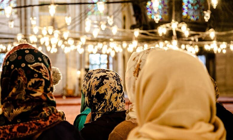 Muslim women wearing hijabs inside a mosque, engaged in prayer or reflection.