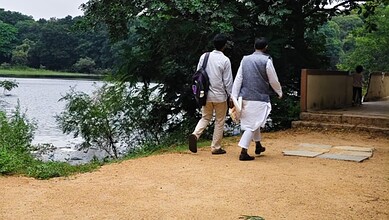 The image shows Muslim students walking ahead, by the lake inside the Osmania University campus in Hyderabad.