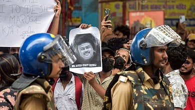 Protesters hold signs and photos amid police officers during a demonstration.