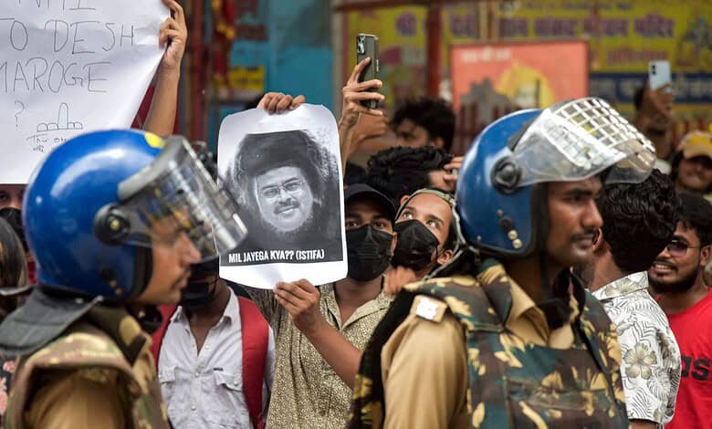 Protesters hold signs and photos amid police officers during a demonstration.