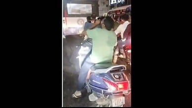 Man riding a two-wheeler while drinking alcohol in Hyderabad, captured at night.