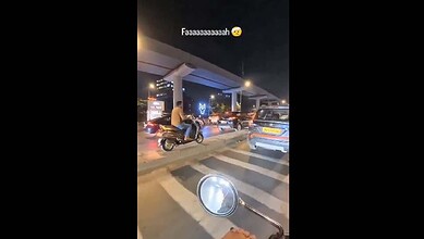Motorcyclist riding without helmet at Hyderabad traffic signal at night.