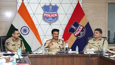 Telangana police officials in a meeting with Indian flags and police emblems in background.