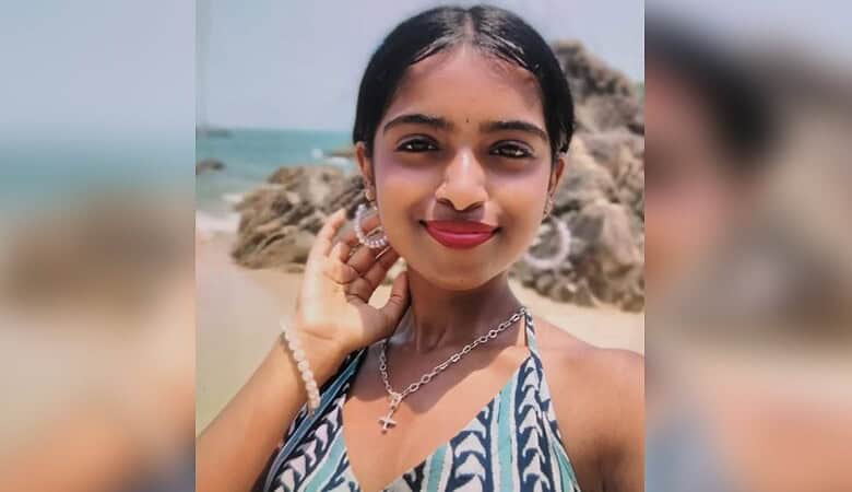 Young girl smiling at Sankey Tank, Bengaluru, with rocks and water in the background.