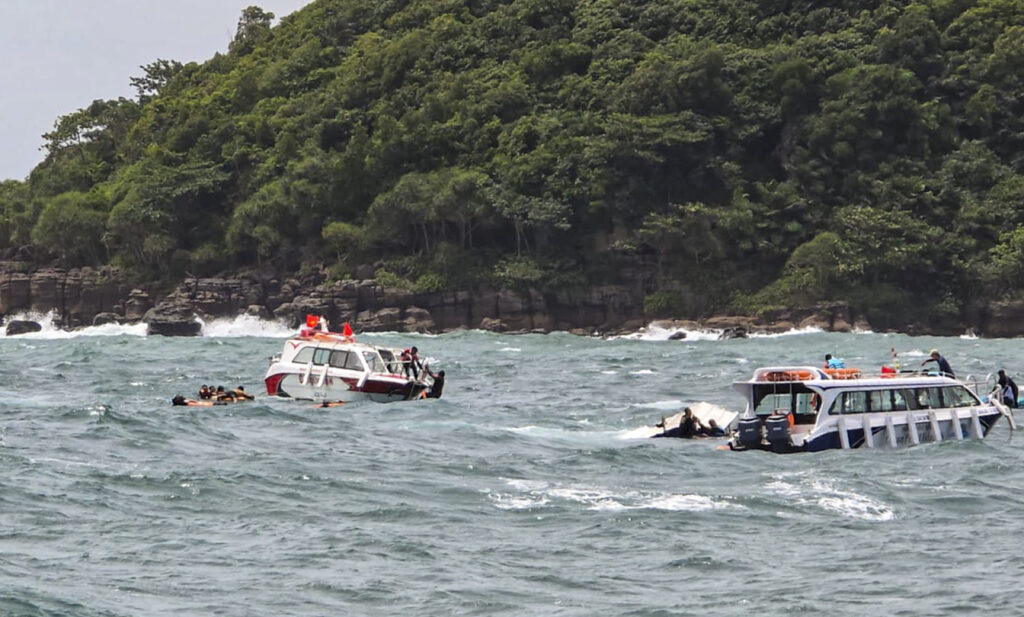 Rescue boats and swimmers in the water near a green, forested shoreline.